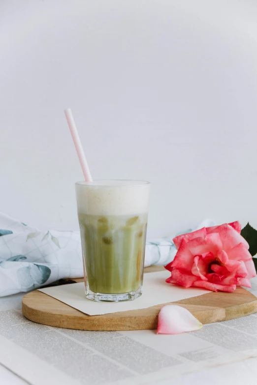 a green beverage sitting in a tall glass on a small board