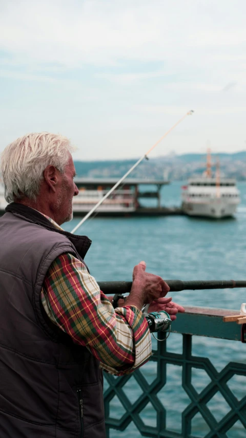 an old man is fishing while standing on a dock