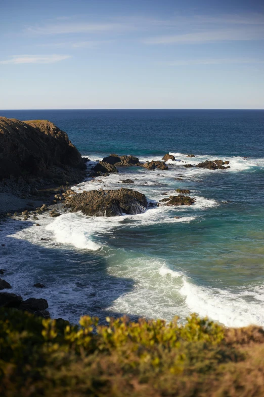 the water is crashing onto the shore near some rocks