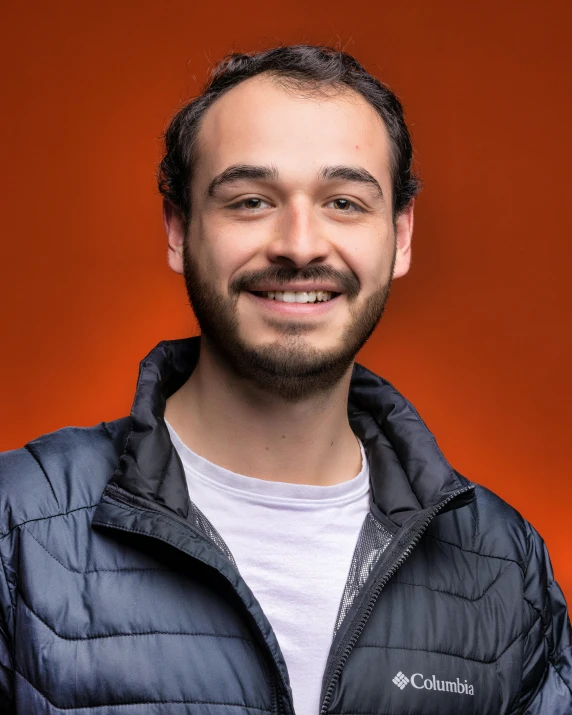 a man smiles while wearing a blue jacket