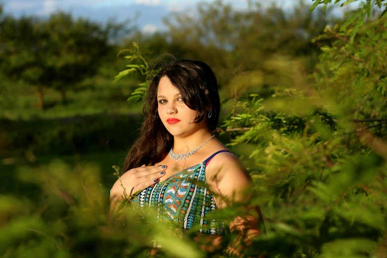 the woman is standing in the grass near many bushes