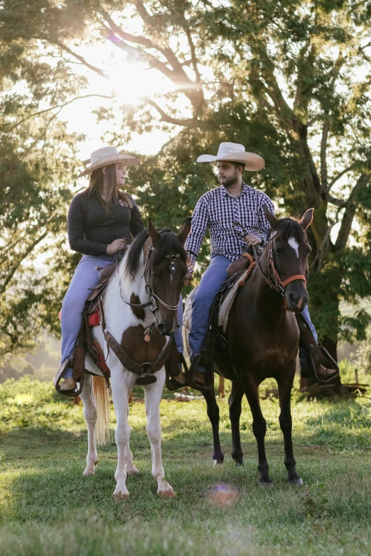 two people wearing hats are riding horses in the park