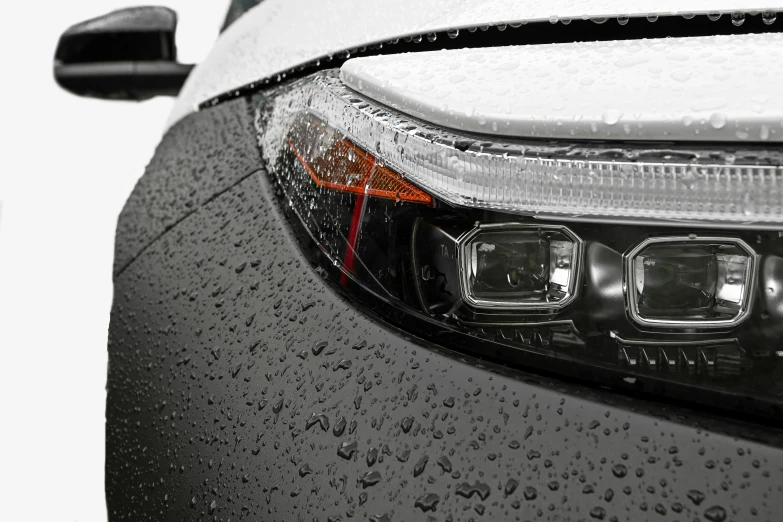 the tail light of a silver sports car covered in raindrops