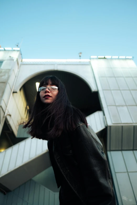 a woman wearing glasses in front of a bridge