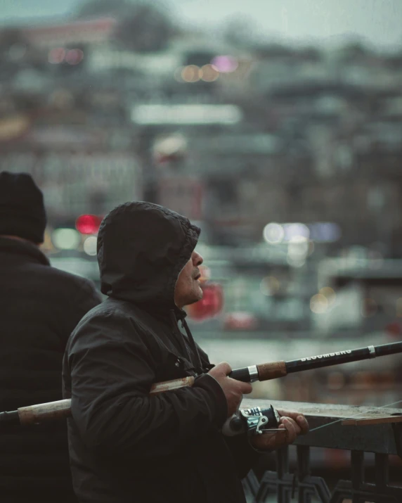 man wearing raincoat and holding fishing pole standing on rooftop