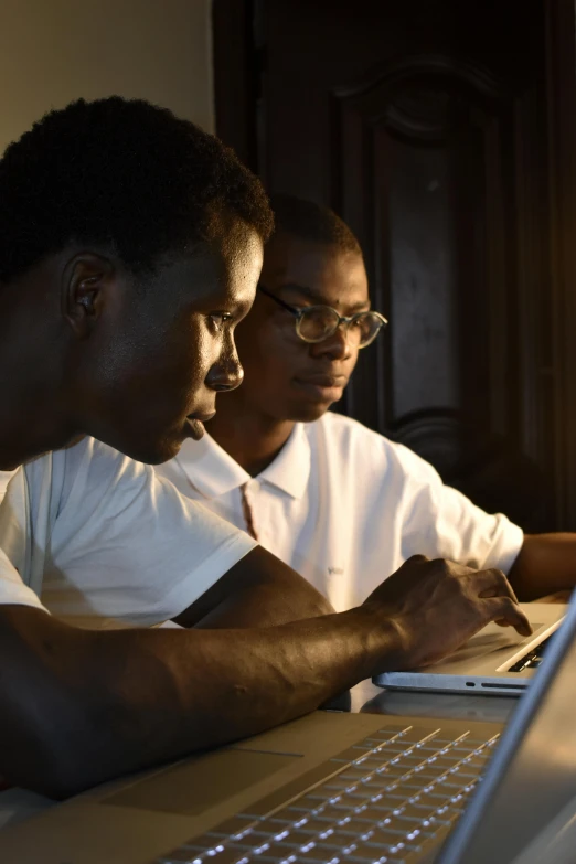 two men sitting at a table with their laptops