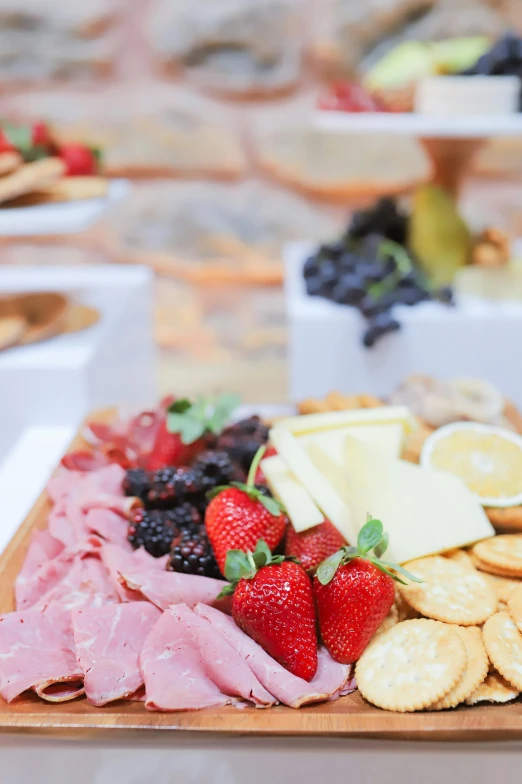 food sitting on top of a  board with cheese, fruits and other meat