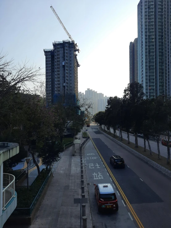 an empty road with a few vehicles in it and tall buildings