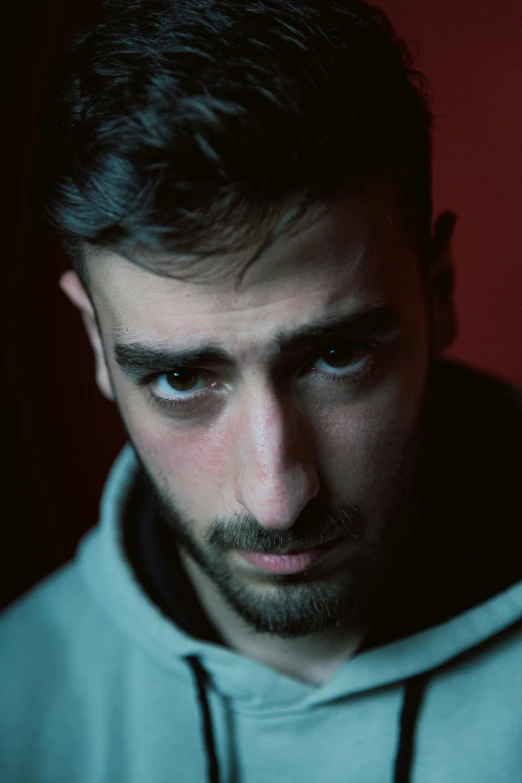 man wearing hooded sweatshirt posing for po taken in dark room