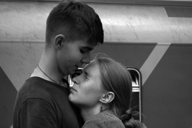 a boy kisses a girl's cheek with her nose