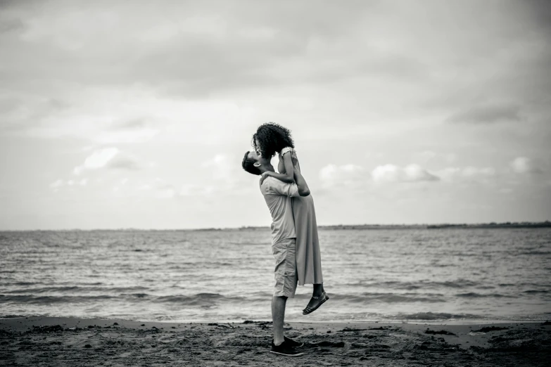 a man standing by the water holding a woman's head