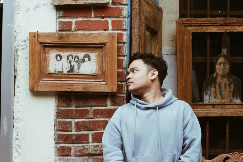 a man is leaning on an old brick building with window panes