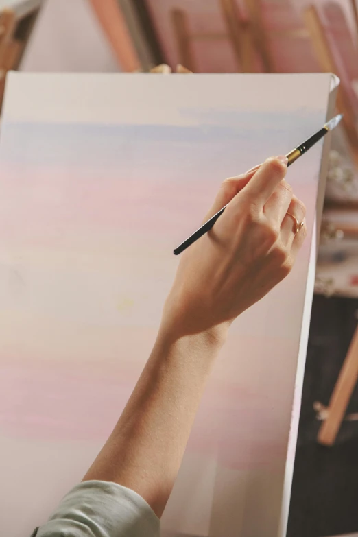 a woman painting a picture with brush in her hand
