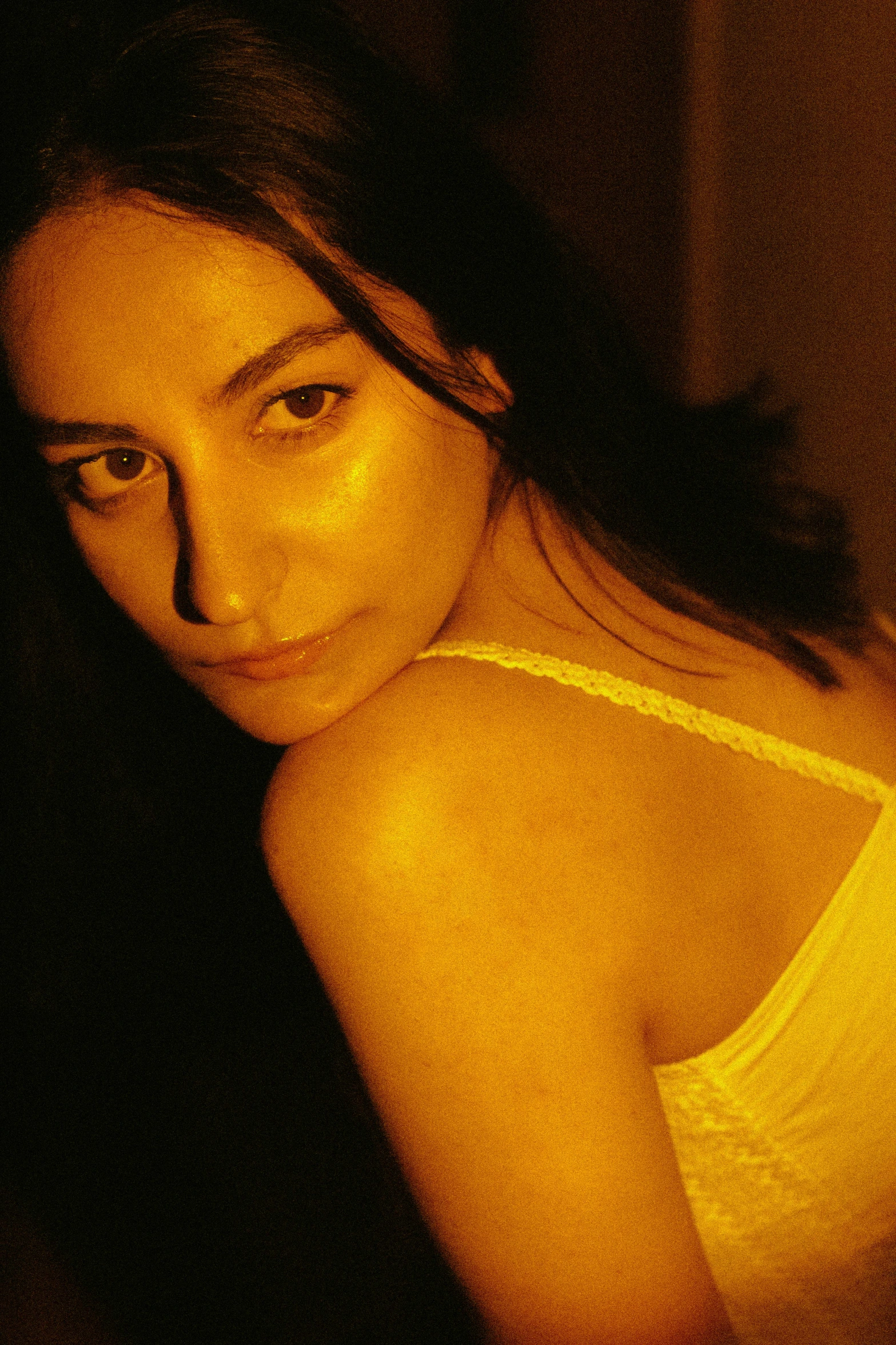 a woman in a white tank top with long dark hair