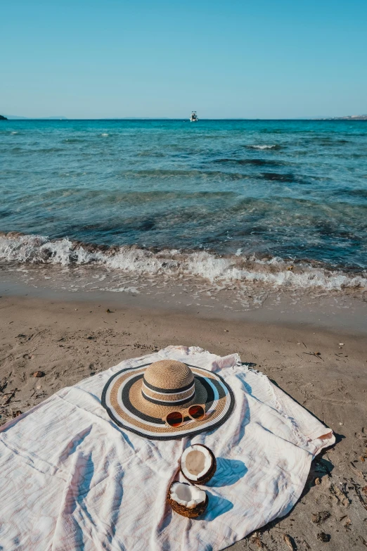 two plates and cups on an white towel on the beach with blue water