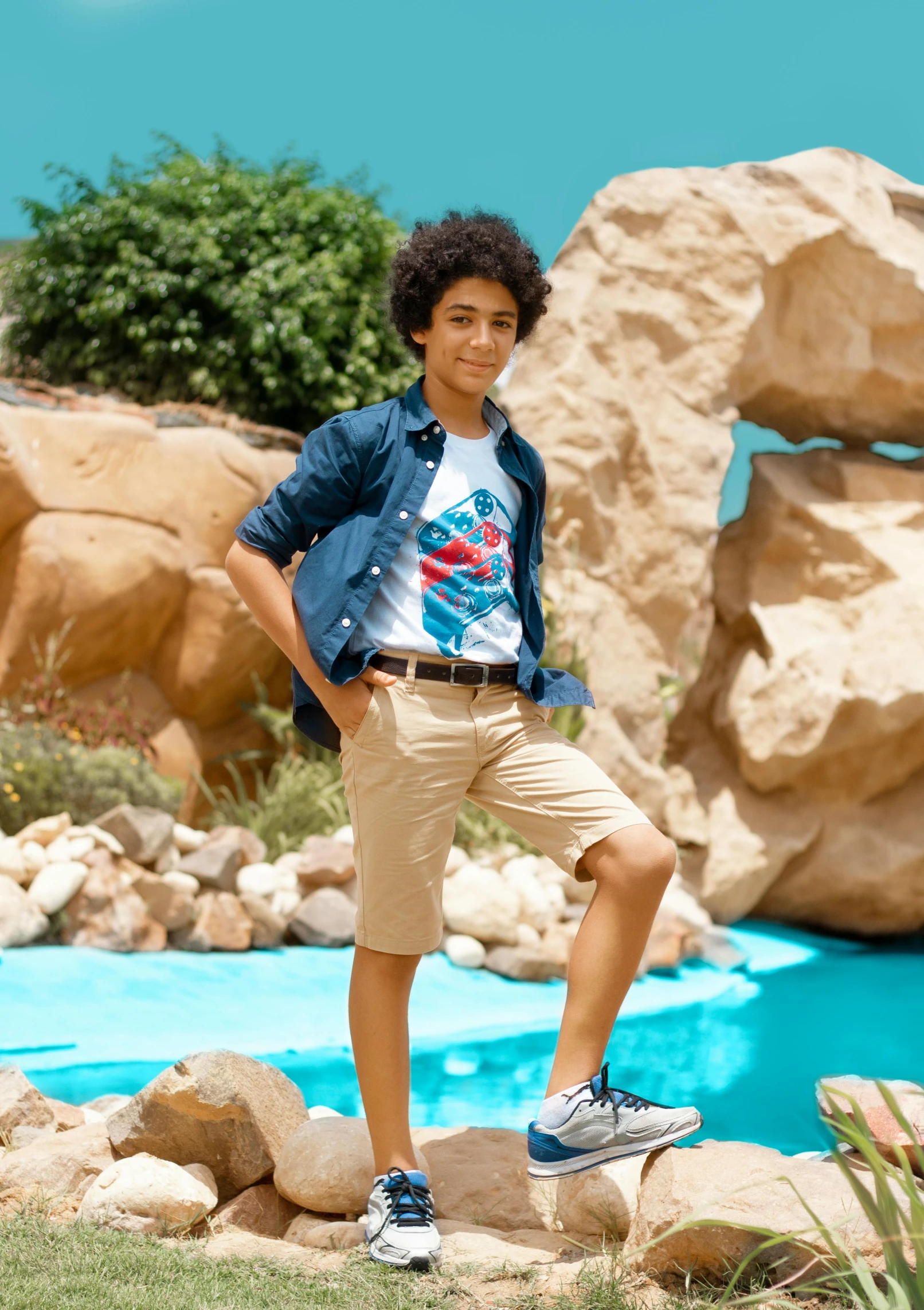 a young man stands in a rocky pool area