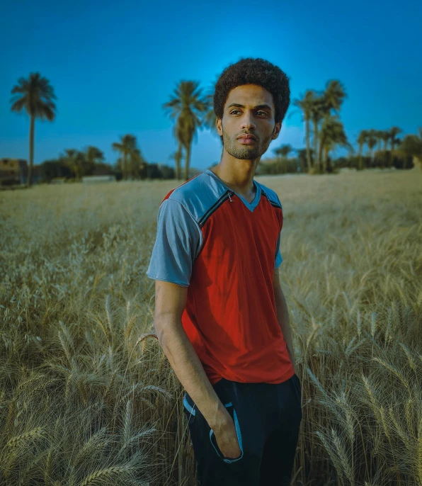 a man in a field with a bright sky and palm trees