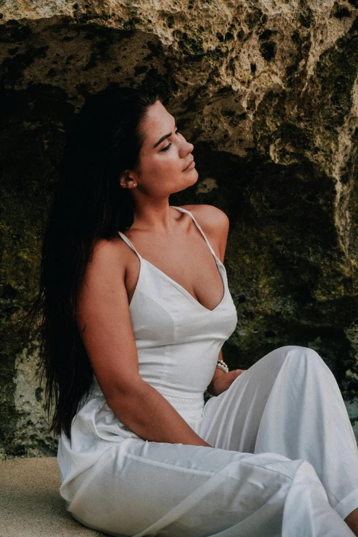 a woman sitting against the stone wall