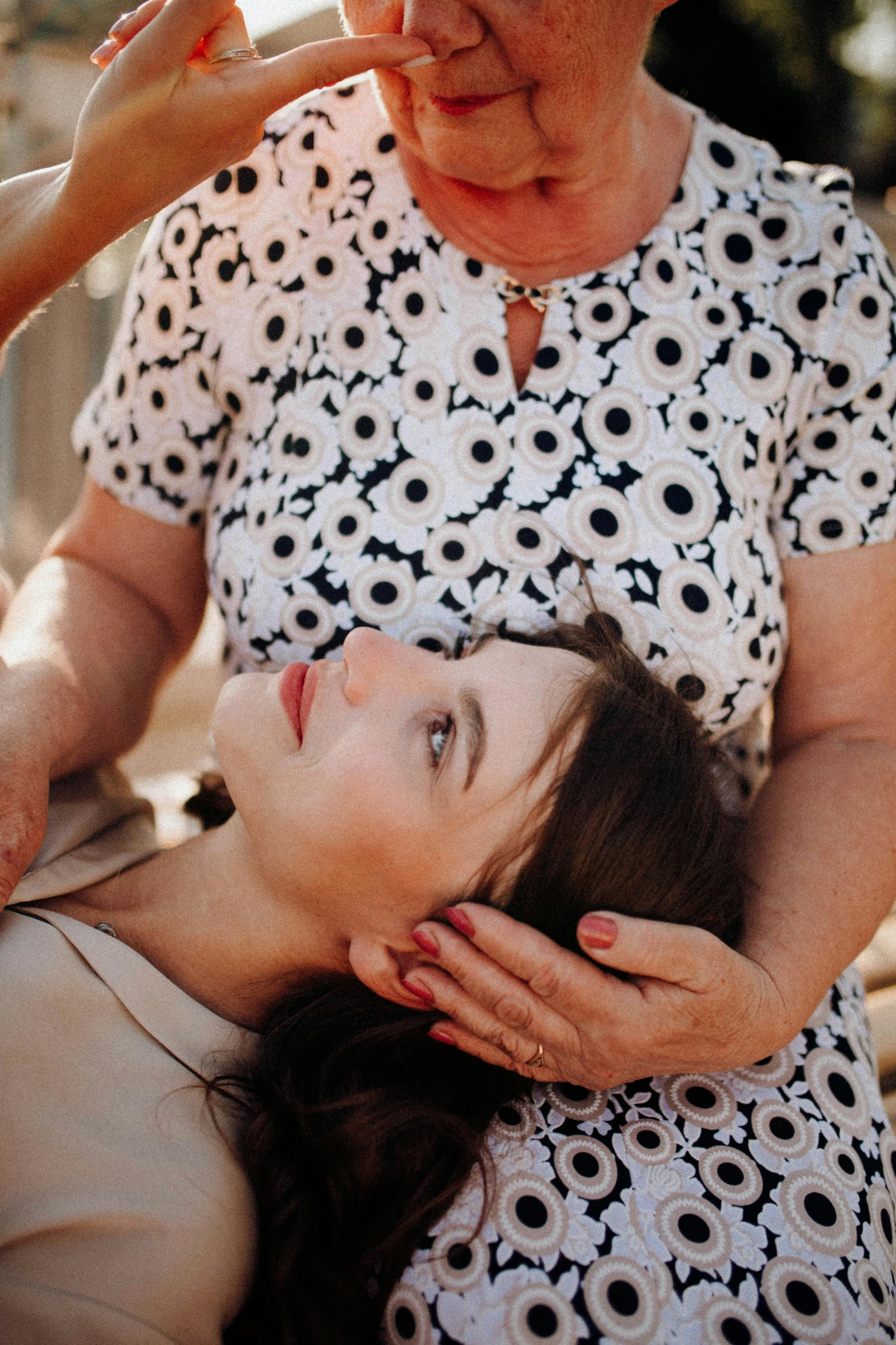 an older woman holding her head with one hand while a woman is holding another