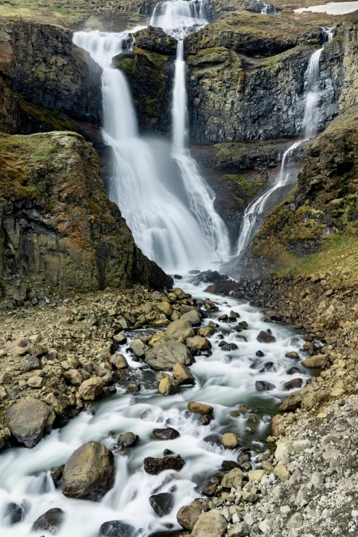 a mountain top with a stream near a waterfall