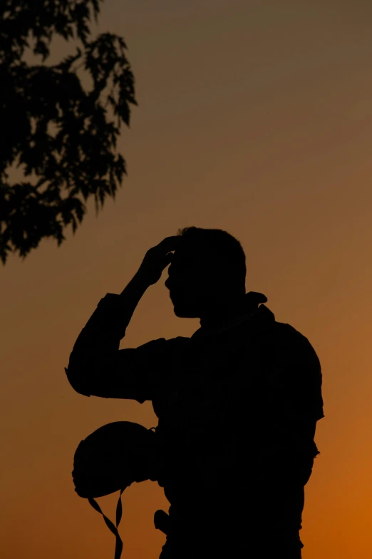 the silhouette of the man is holding his head while he looks at the sunset