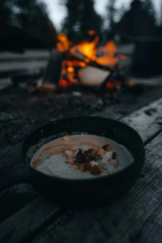 bowl of soup sitting on table near fire