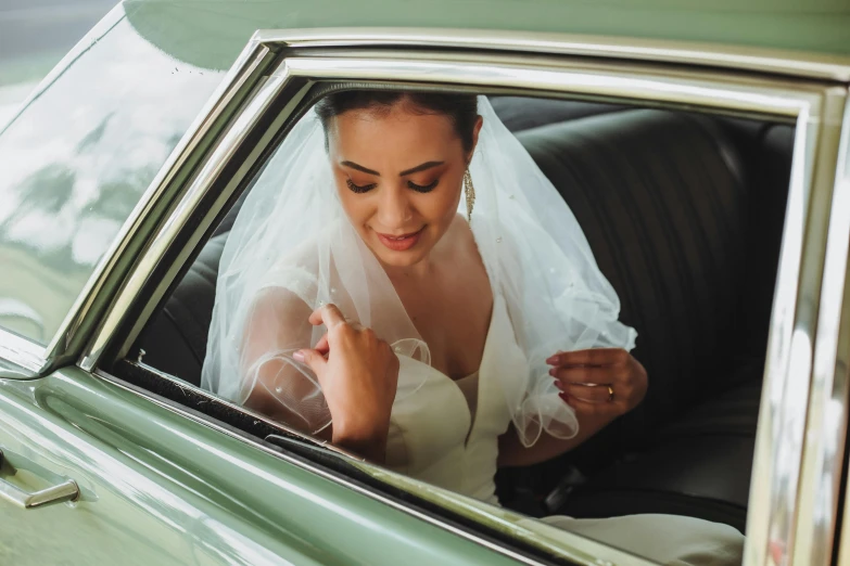 a bride sitting in a car holding up a piece of paper
