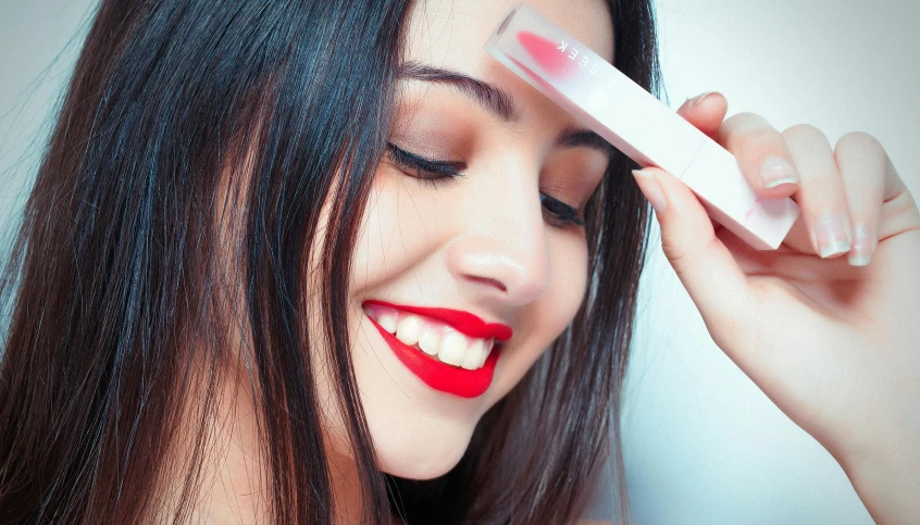 a woman putting lipstick on her forehead while she brushes her hair