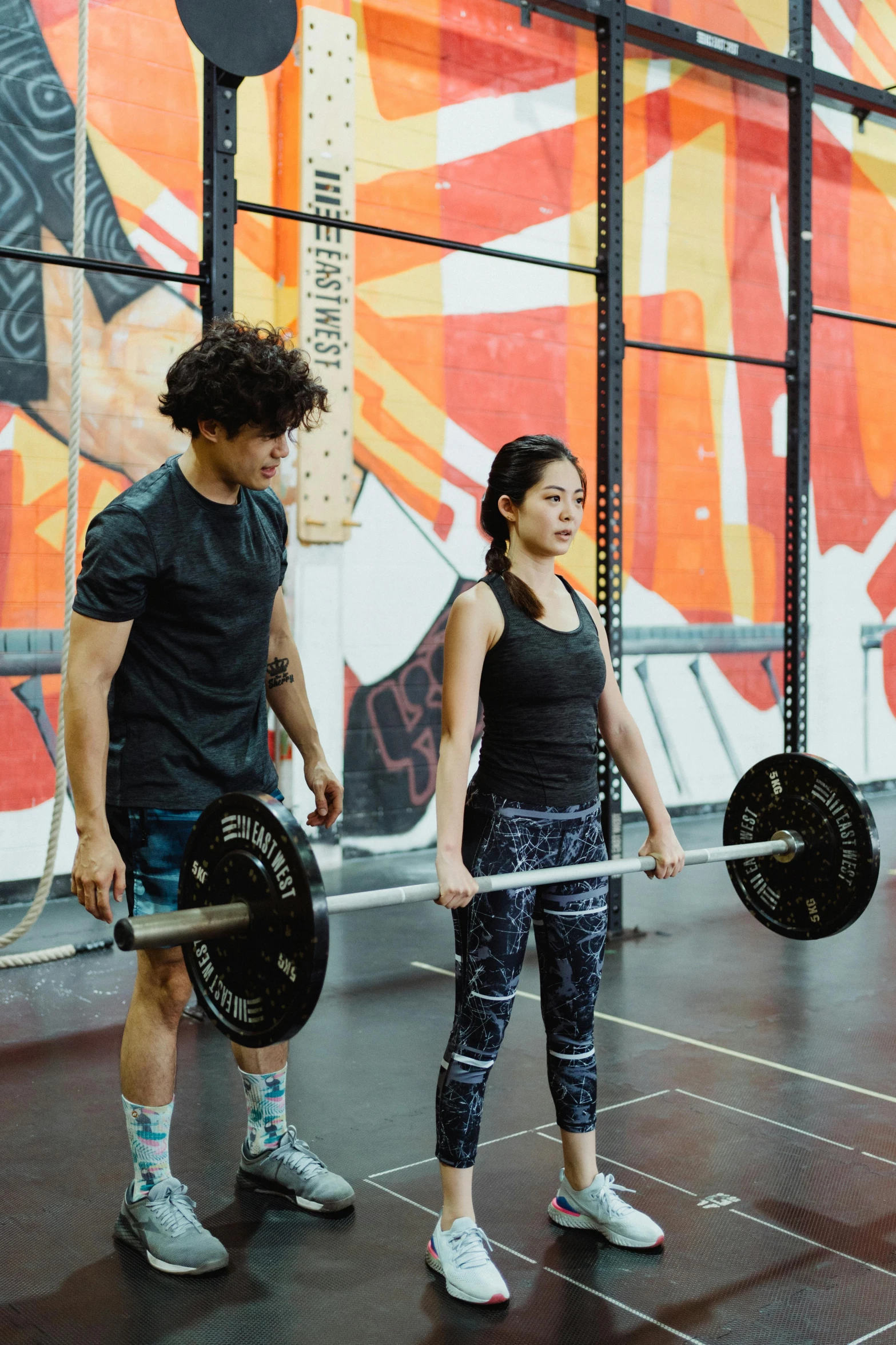man and woman lifting a barbell at a gym