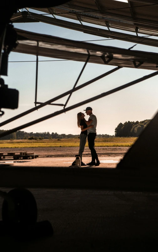 a couple is kissing underneath the wing of a airplane