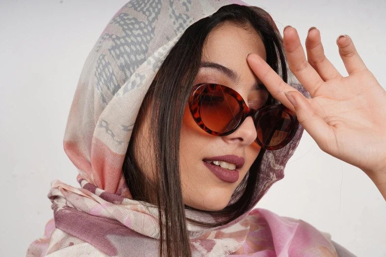 a woman in a scarf and sunglasses covering her eyes