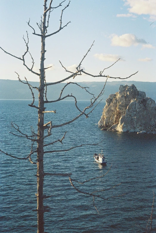 a boat is seen in the distance in a body of water near some rocks