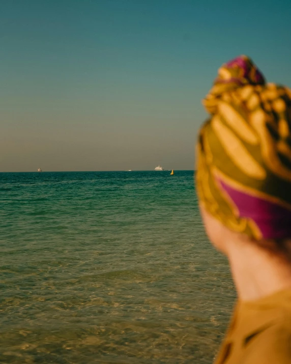 a person is standing on the beach near a sailboat