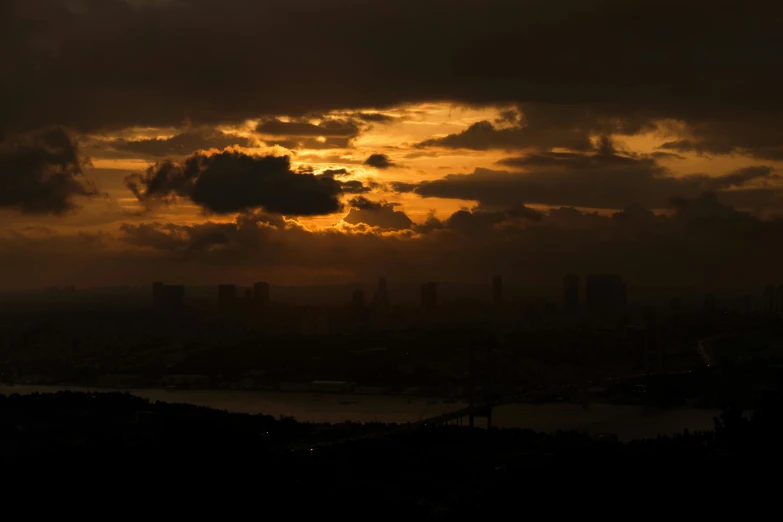 the sun is setting and a few clouds are seen over a city