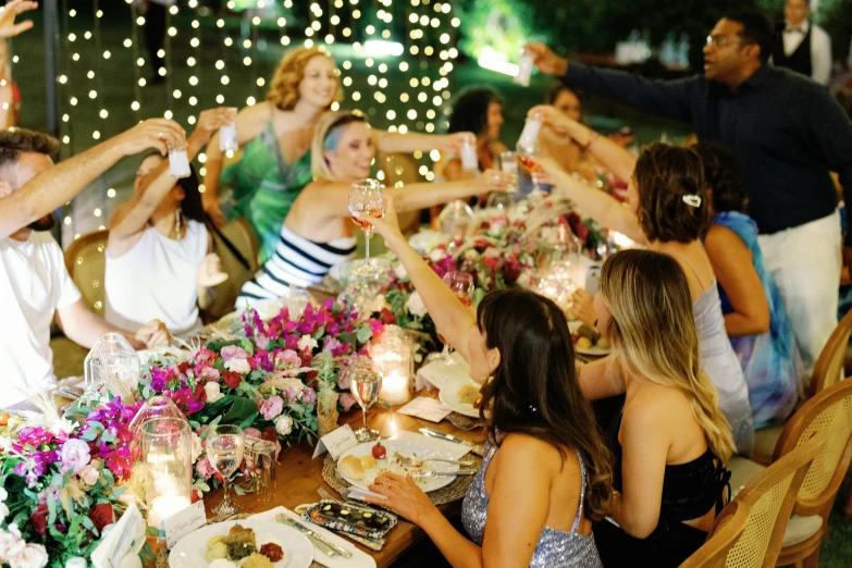 several people sit at tables with plates and drinks