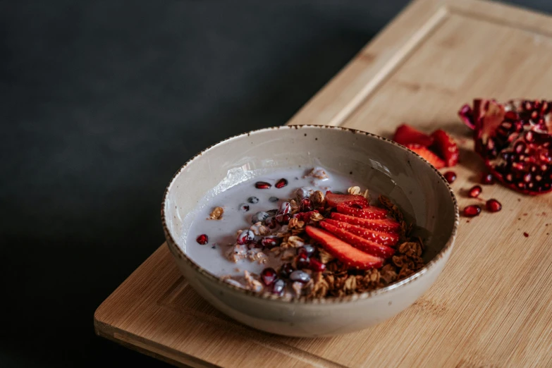 a bowl of food on a board next to some pomegranates