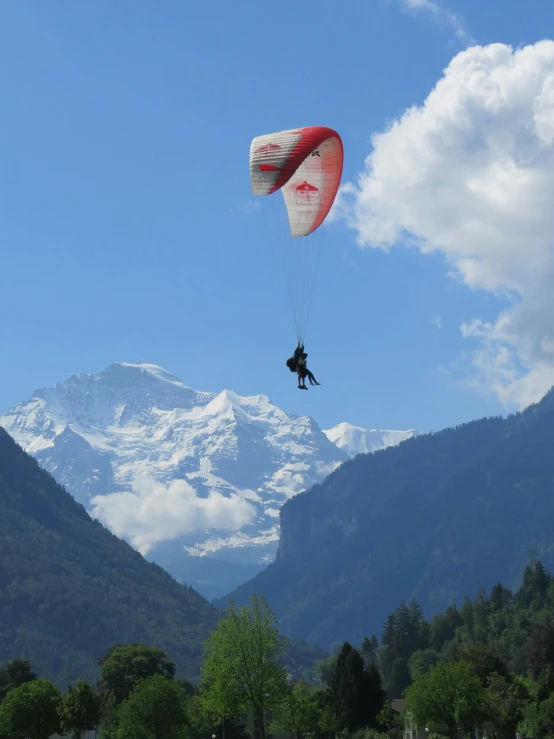 a man flying a kite on the ground near the mountains