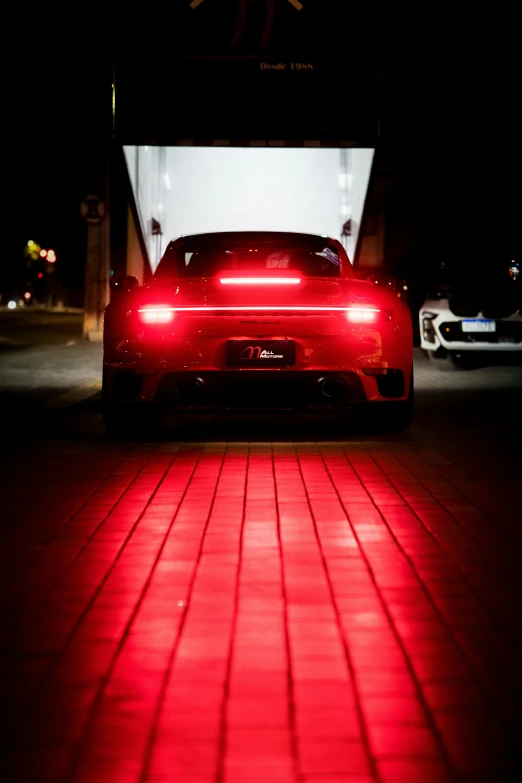 car on street illuminated by red headlights at night