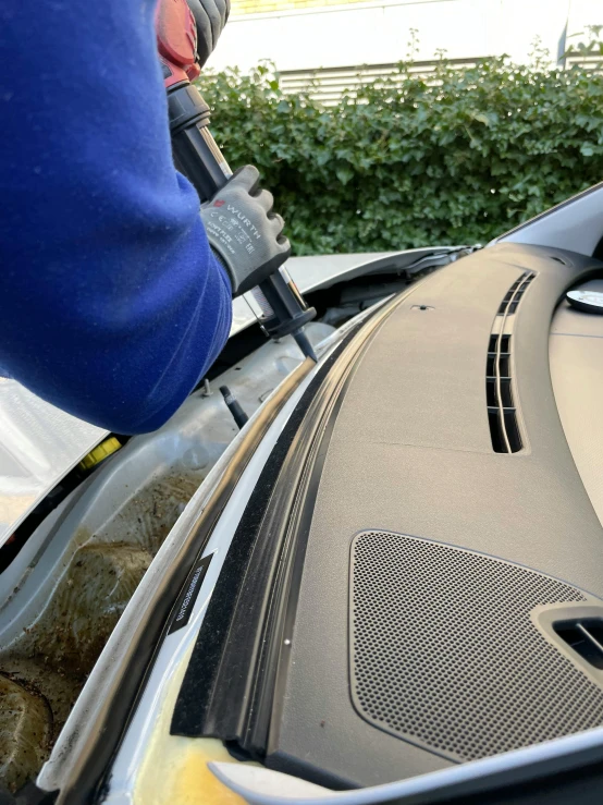 someone holding a brush to clean an empty vehicle hood