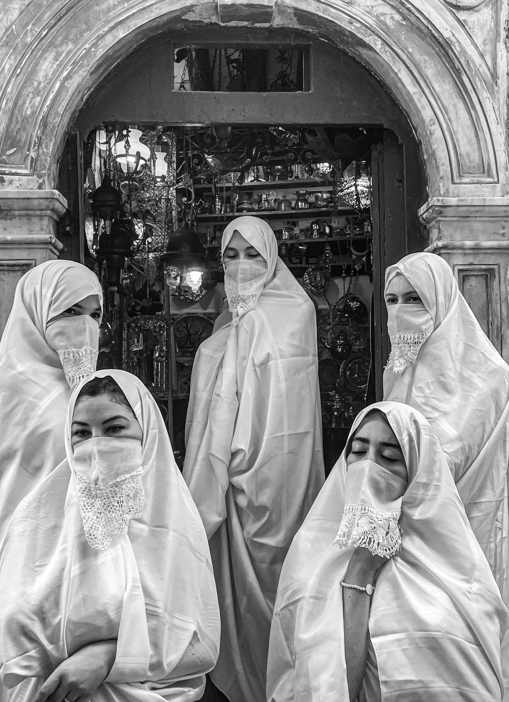 three girls in white robes in front of an arch