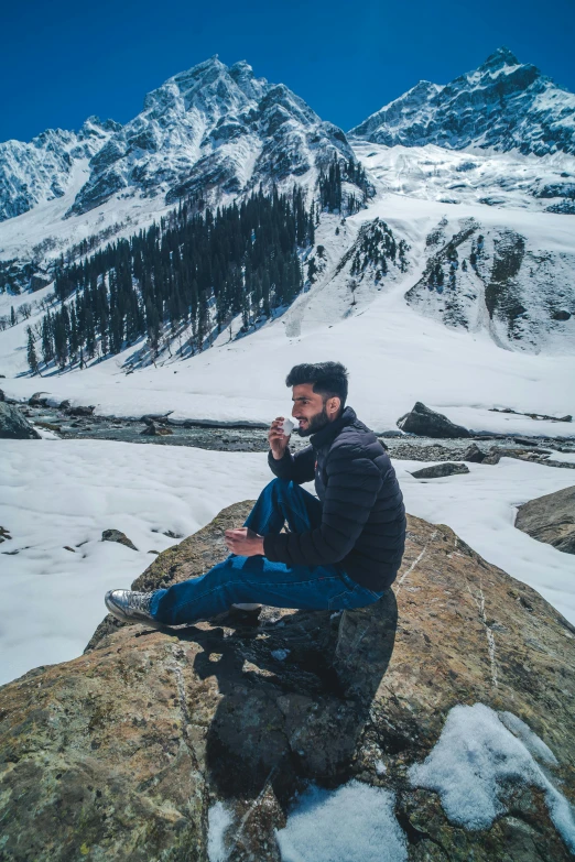 a man sitting on a rock while he smokes