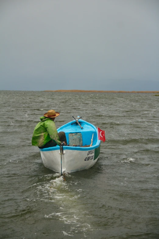 man rowing small row boat in open sea water