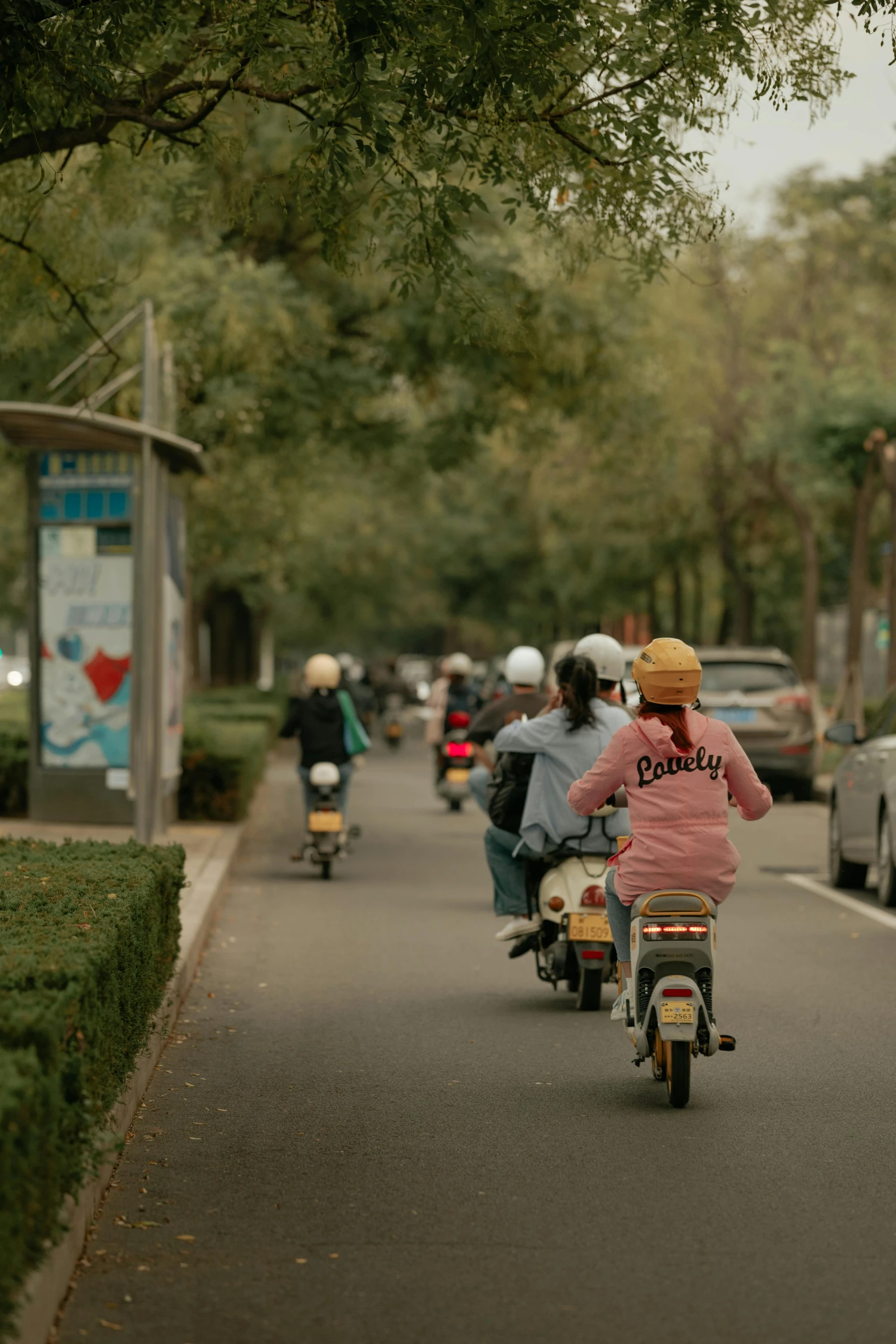 two women riding motor scooters on a city street