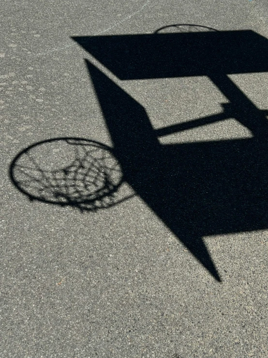 shadow of tennis racquet and basket on the ground