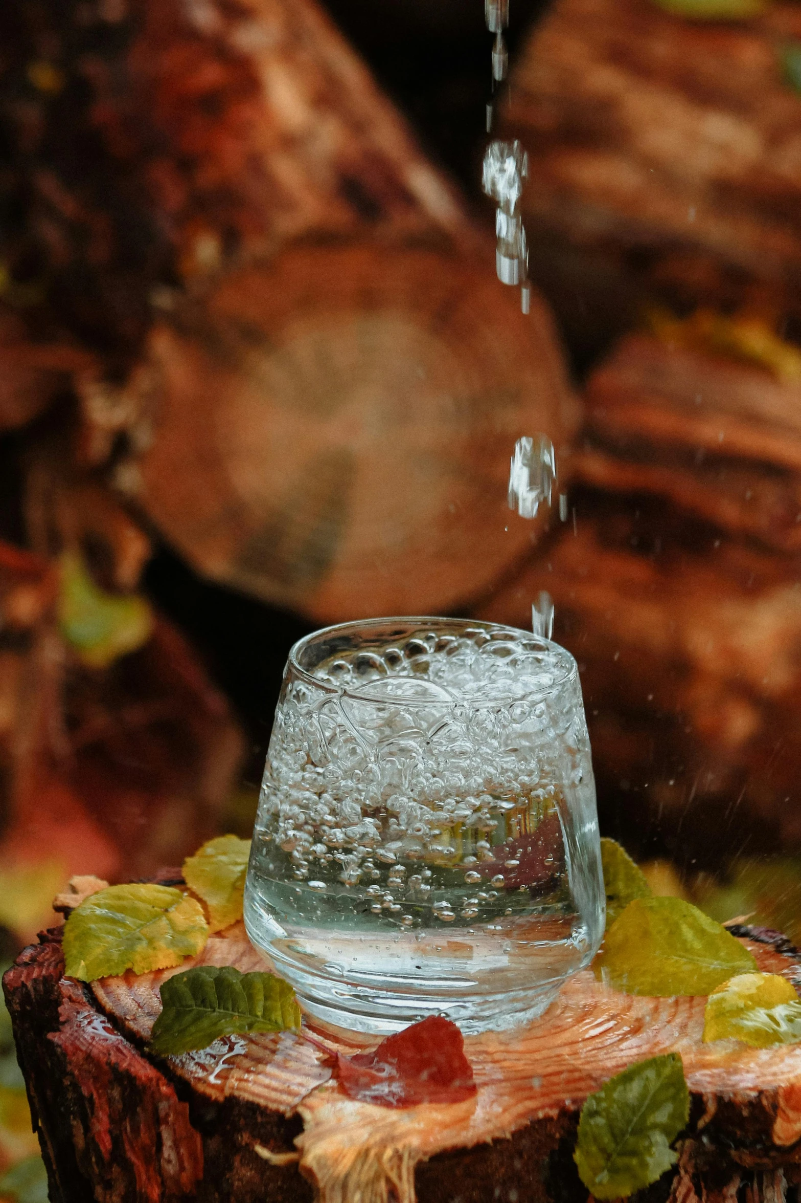 a glass container is being held on a stump with water pouring