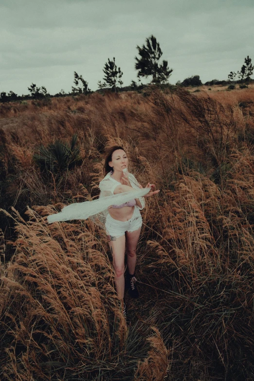 the woman in a long white dress is posing in tall grass