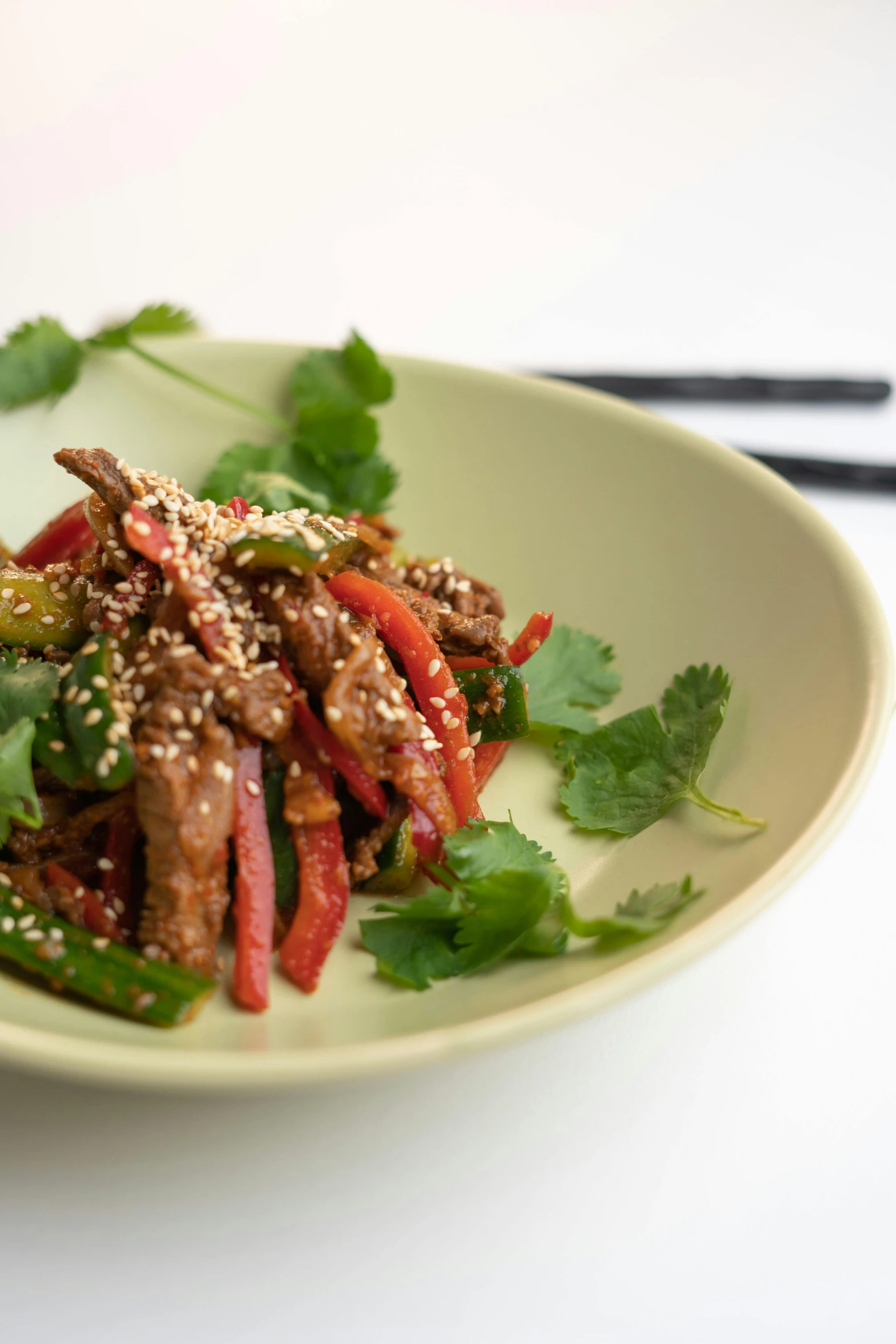 meat and vegetables in sauce on a plate with chopsticks