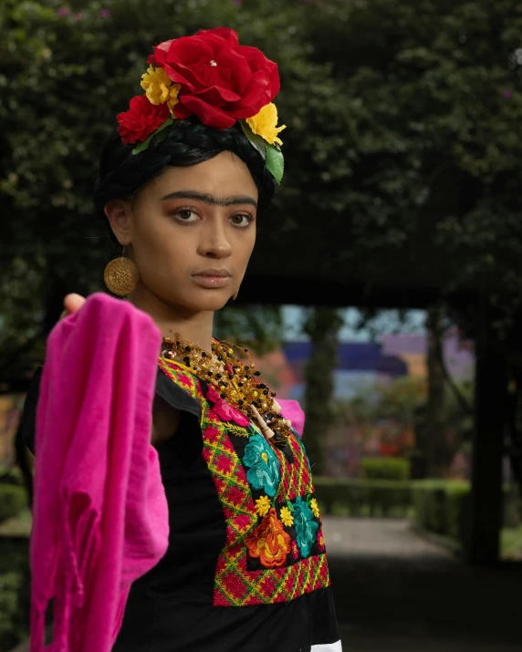 a young woman in traditional mexican clothing stands outside