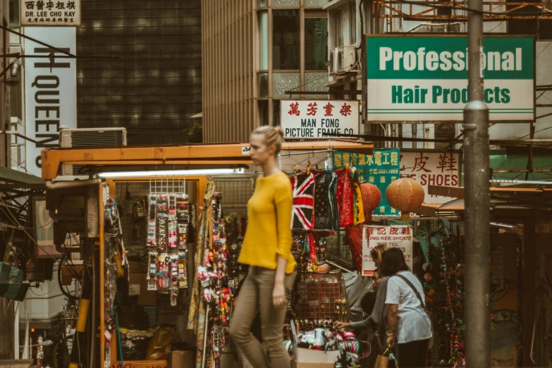 a woman in yellow is walking past some stores