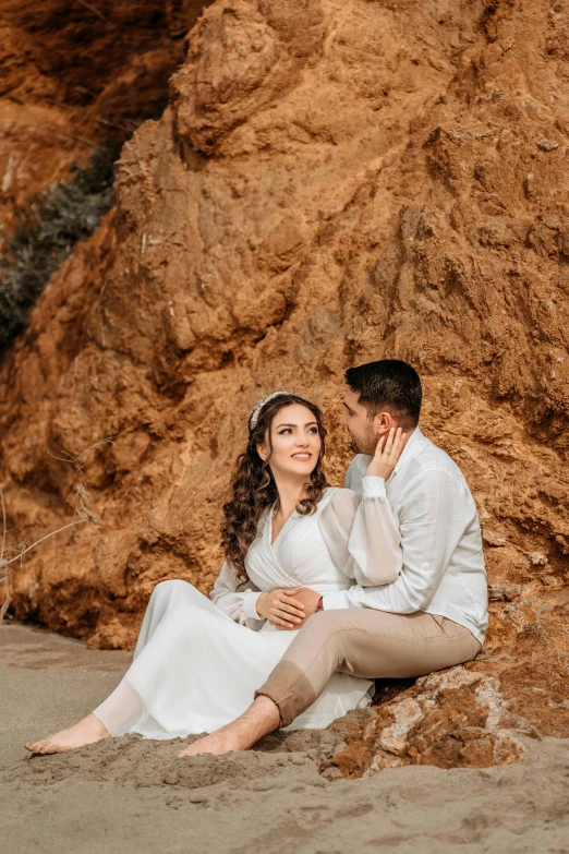 a man and a woman sitting on the beach with sand on their feet